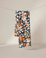 The GEOMETRY Wings in the Wind towel, featuring a vibrant orange, black, and white butterfly wing pattern, hangs neatly on a clothesline against a plain light background.