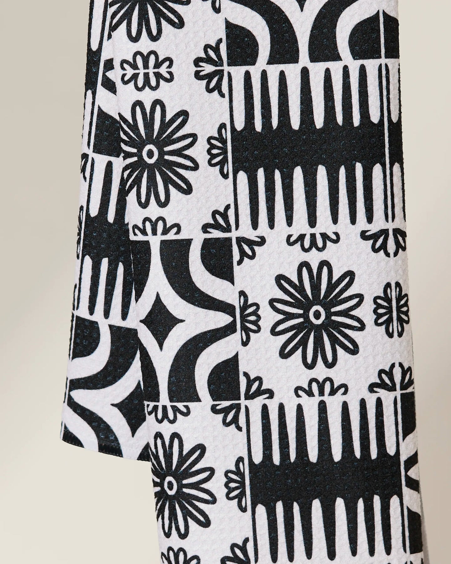 The GEOMETRY Bohemian Mosaic is a quick-drying towel showcasing black and white geometric and floral motifs—daisies, diamonds, and abstract shapes—in a repeating grid design.