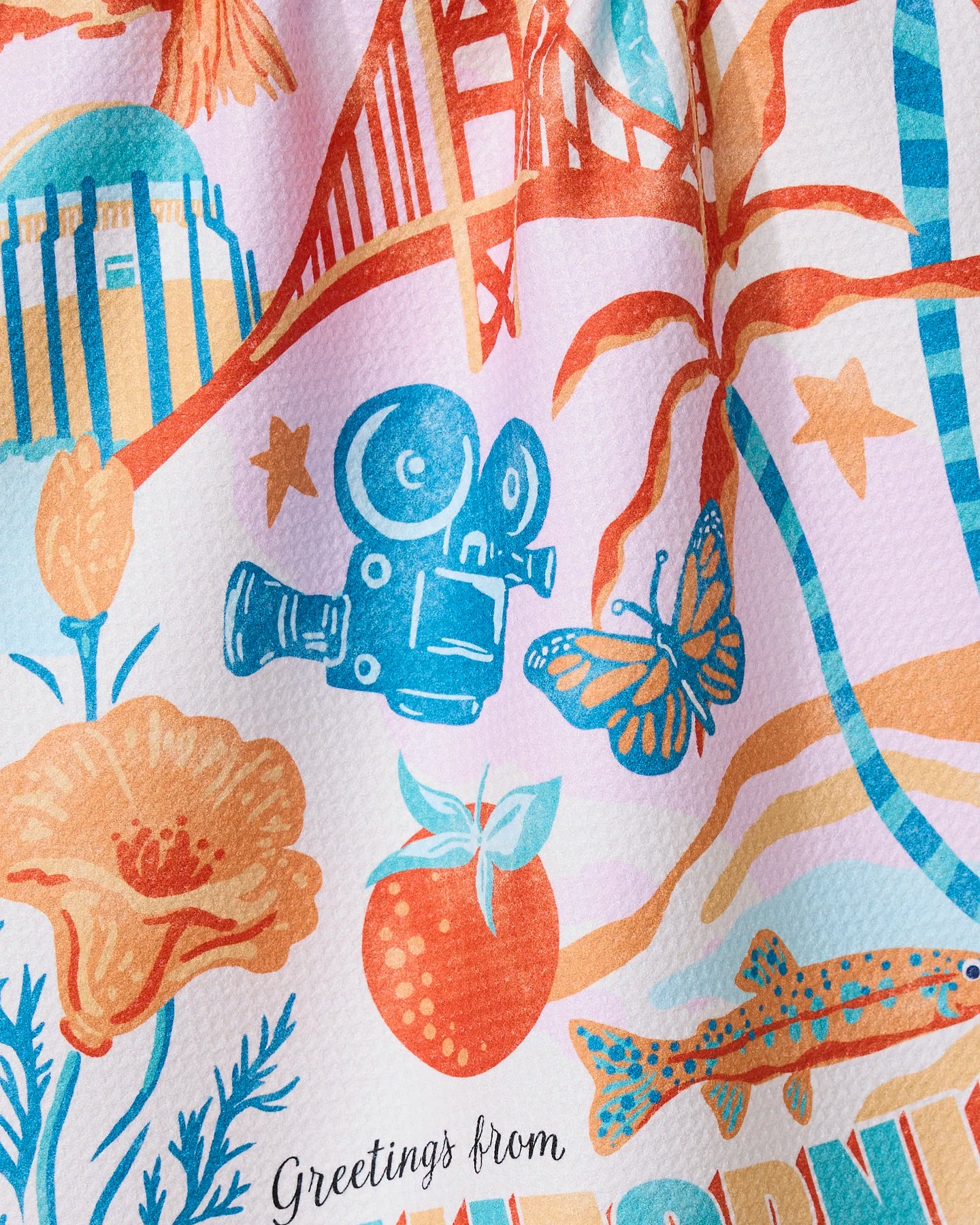 Geometry’s “Greetings From California” tea towel features a colorful design with a vintage movie camera, butterfly, strawberry, orange poppy, fish, iconic landmarks, and “Greetings from”—made from ultra-absorbent recycled materials.