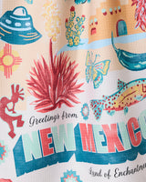 Geometry’s “Greetings From New Mexico” dish towel features a vibrant design with New Mexico icons—UFO, cactus, chili pepper, Kokopelli, fish, adobe building, and Zia sun symbol—plus the text “Greetings from NEW MEXICO Land of Enchantment.”.
