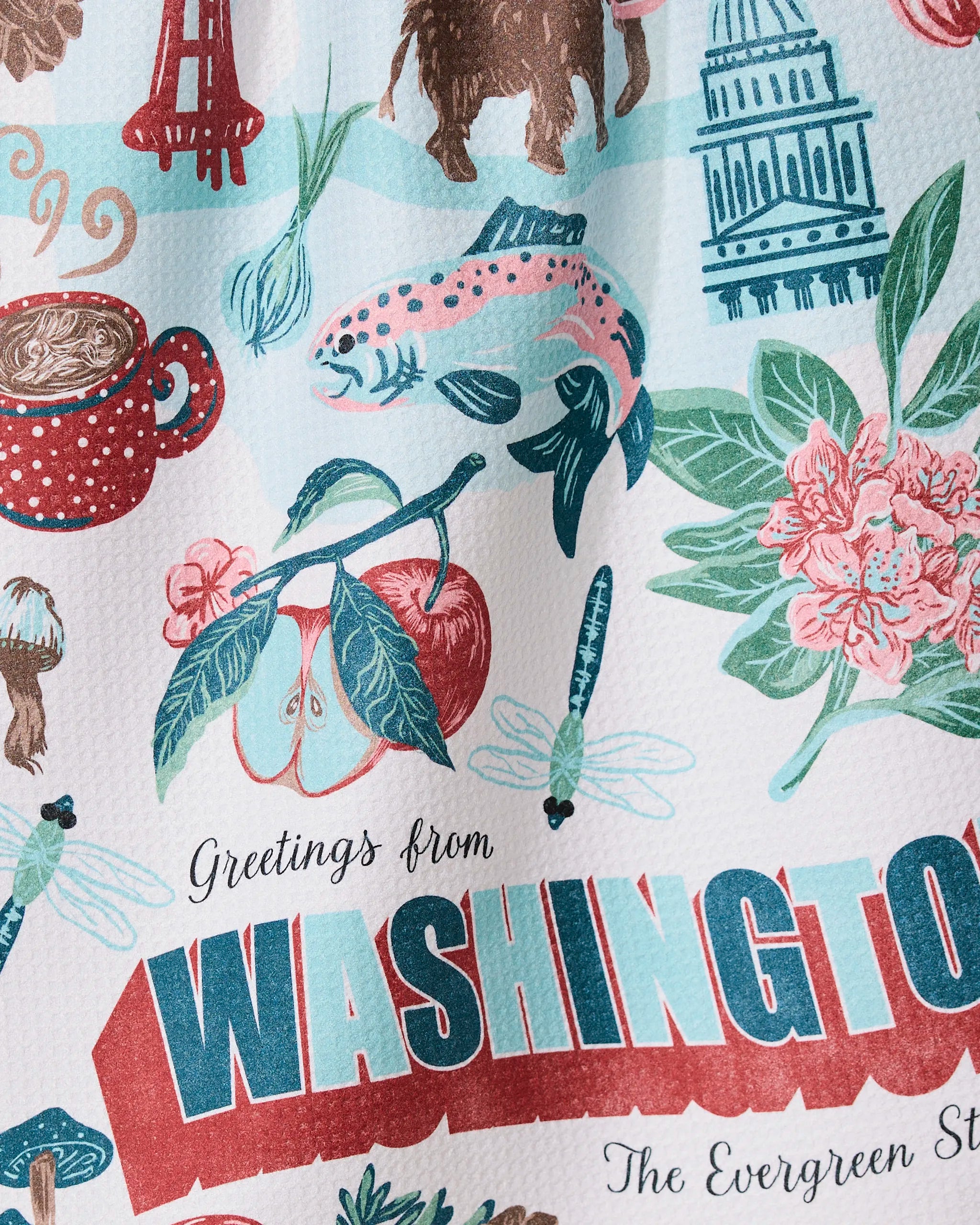 The Geometry Greetings From Washington tea towel features ultra-absorbent fabric and colorful illustrations of state symbols like salmon, apples, cherries, Mt. Rainier, the Capitol dome, flowers, and trees with greeting text.