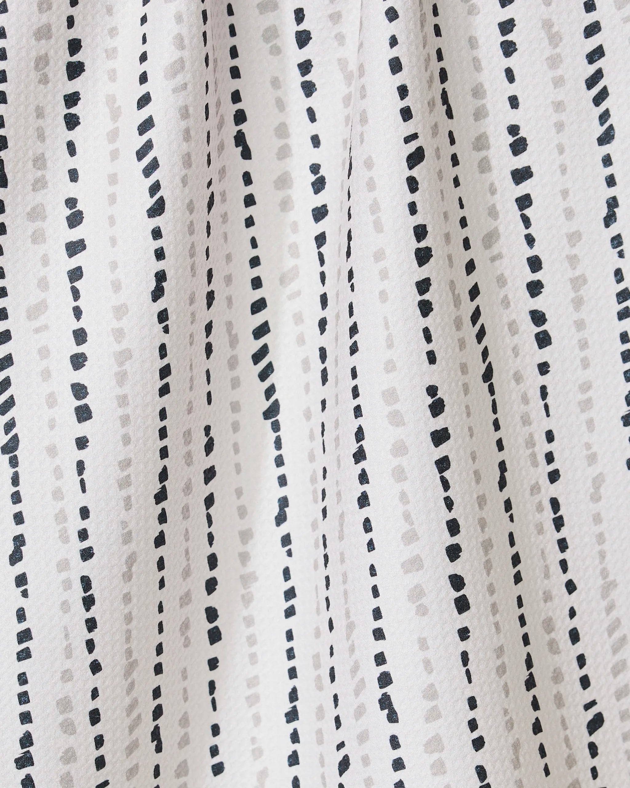 The GEOMETRY Grey Prints recycled kitchen towel features a simple, modern look with white fabric and vertical dotted lines in black and light gray, creating a textured and dynamic appearance.