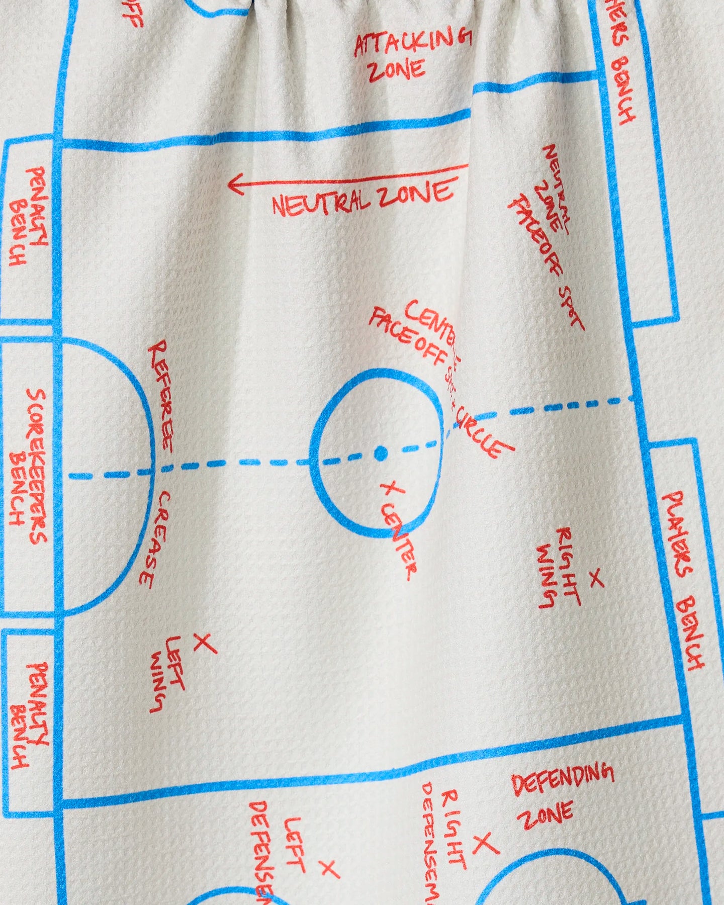 The GEOMETRY Hockey tea towel features a blue and red hockey rink diagram labeling zones and player positions. Made from recycled materials, this unique white kitchen towel is perfect for sports fans.