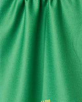 Close-up of a green, textured I Love Pickleball tea towel by GEOMETRY. Made from recycled materials, it has soft folds, a subtle sheen, and yellow text partially visible near the bottom edge.