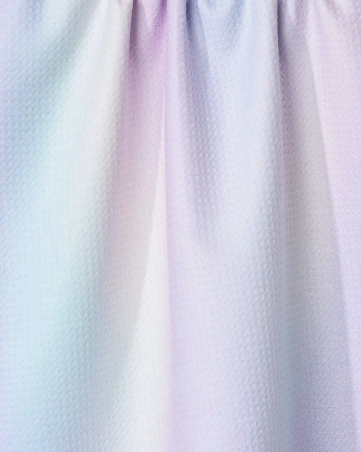 Close-up of the GEOMETRY Iridescence tea towel, featuring pastel hues of light blue, pink, and purple with a textured finish. The ultra-absorbent kitchen towel has soft folds and is gently gathered at the top.