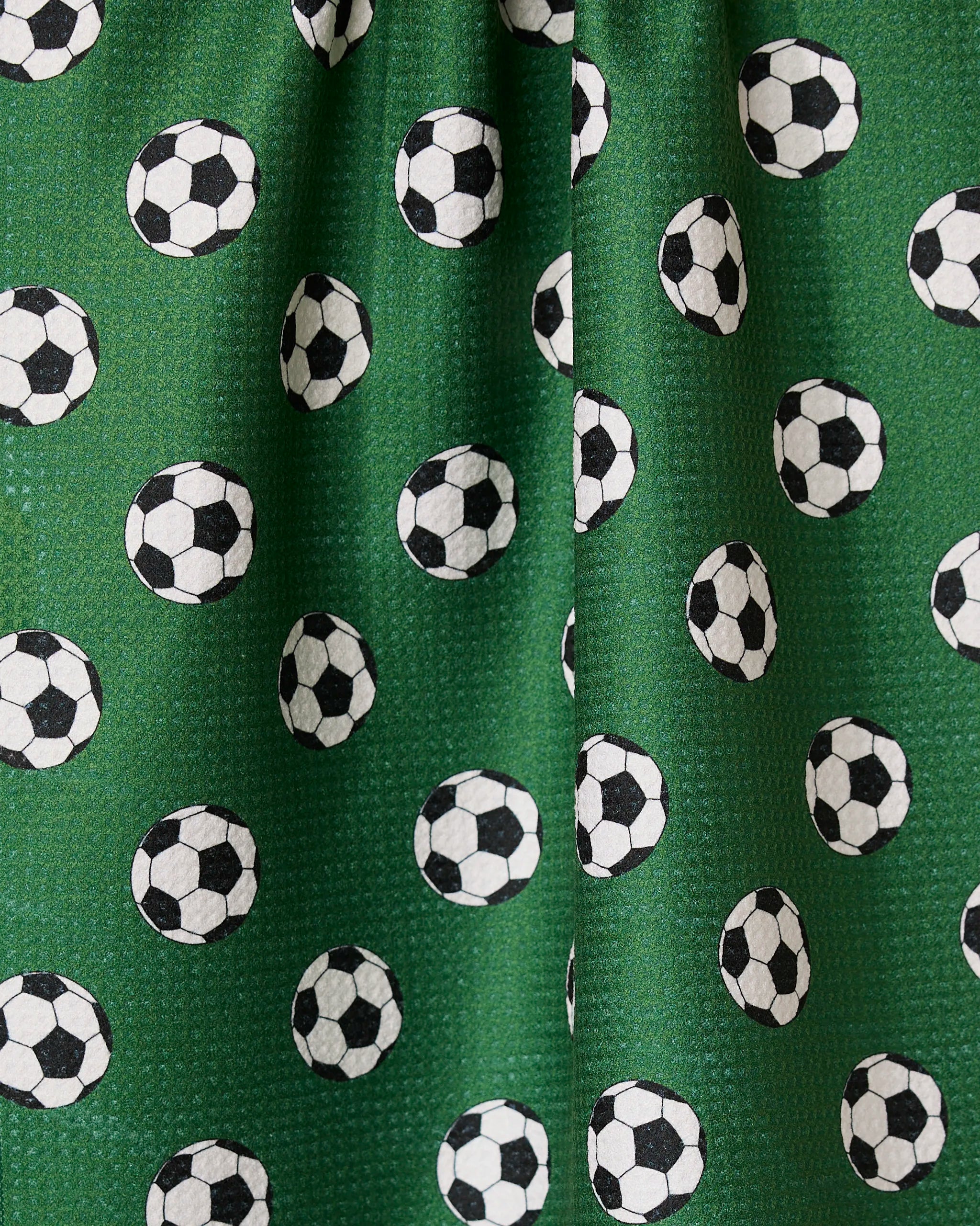 Kick Off by GEOMETRY features green fabric with a playful black-and-white soccer ball print—an eco-friendly towel that adds fun and function to your kitchen as a stylish, absorbent dish or hand towel.