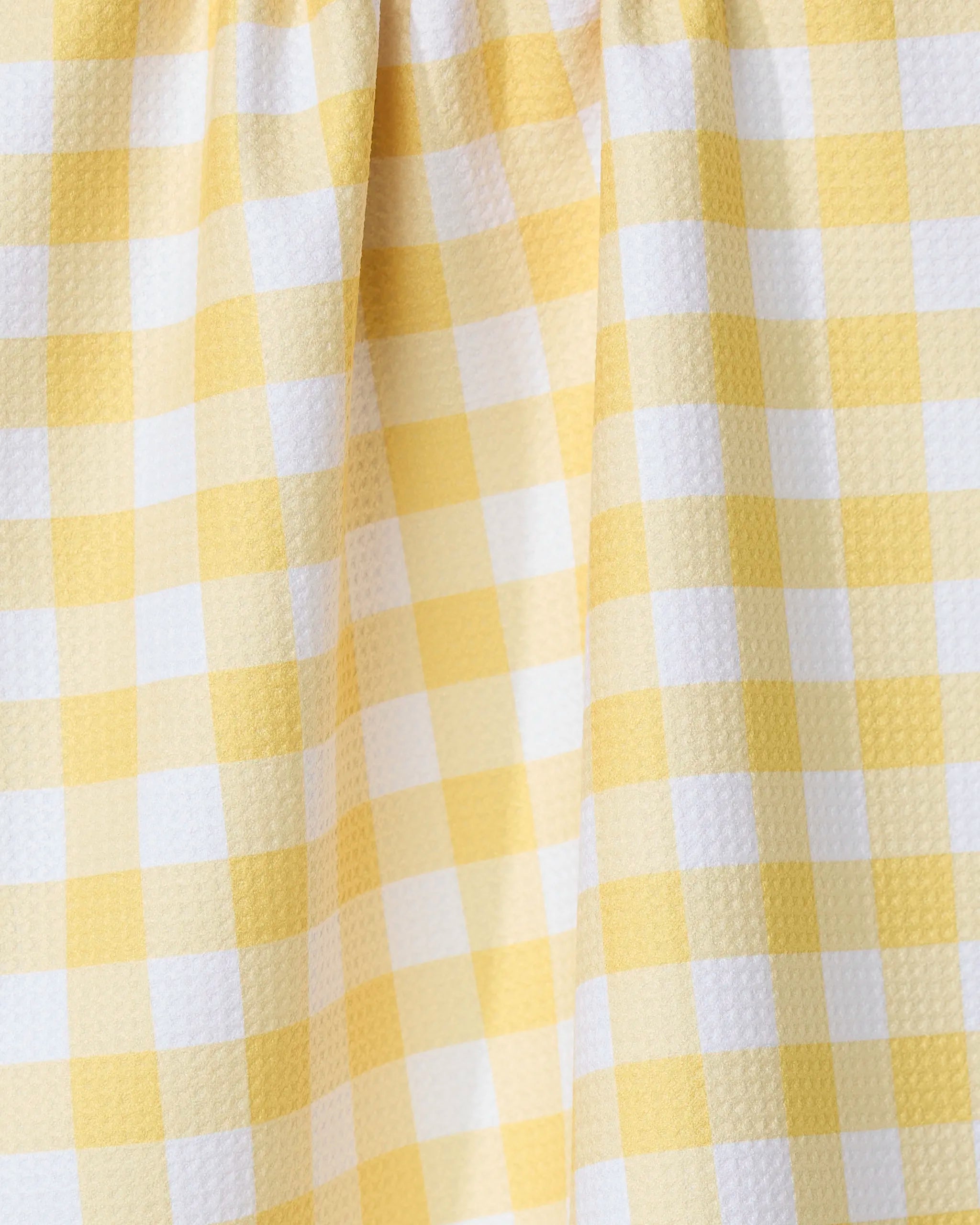Close-up of the GEOMETRY Lemon Gingham recycled kitchen towel, featuring yellow and white gingham pattern with small textured squares and gentle folds.