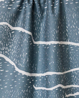 Close-up of GEOMETRY’s Wetlands - Midnight dish towel, featuring a blue-gray absorbent fabric with white abstract wavy lines and dash patterns for a textured, artistic look.