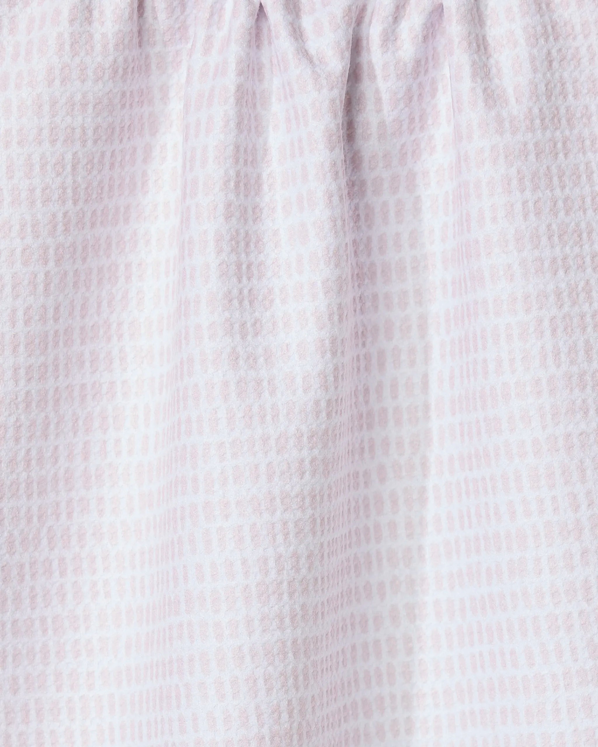 Close-up of Geometry’s Dot Dot Dot Blushed Bergamot kitchen towel, made from recycled fabric in light pink and white with a subtle grid-like dotted pattern. The gathered top creates soft folds and a textured look.