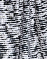 Close-up of Geometry’s Dot Dot Dot Fresh Linen kitchen towel, featuring a grid-like pattern of irregular black dots on white recycled fabric with a lightly gathered, textured look.
