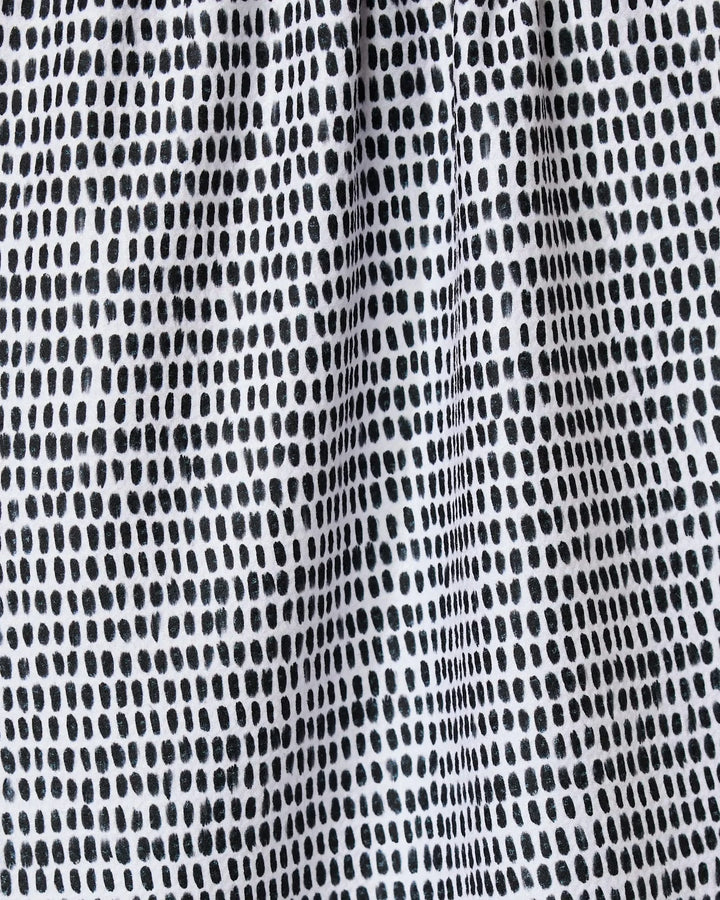 Close-up of Geometry’s Dot Dot Dot Fresh Linen kitchen towel, featuring a grid-like pattern of irregular black dots on white recycled fabric with a lightly gathered, textured look.