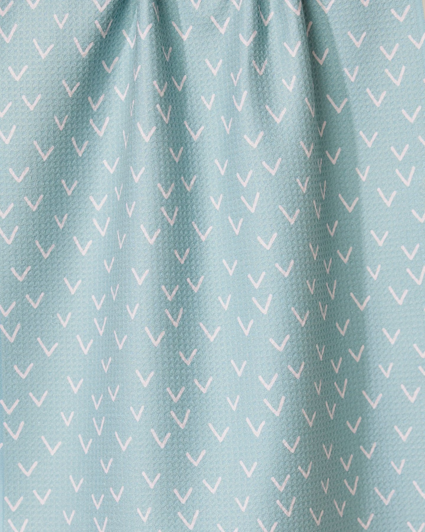 The Drawn Doves tea towel by GEOMETRY features a light blue color with small white check marks in diagonal rows, made from quick-drying fabric and gently gathered at the top.