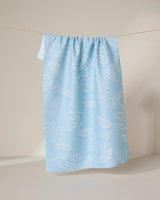 GEOMETRY’s Ediths Embroidery curtain features a light blue hue with white floral patterns, made from recycled materials, and is shown hanging by a string against a neutral background.
