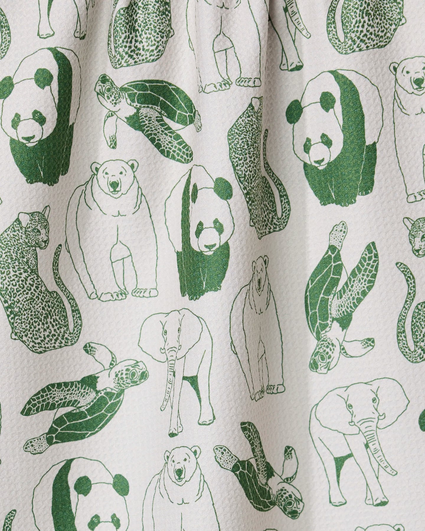 The GEOMETRY Endangered tea towel is white and textured, made from quick-drying recycled material, and features a seamless pattern of green line drawings of pandas, sea turtles, leopards, polar bears, and elephants.