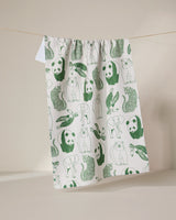 The GEOMETRY Endangered tea towel, made from recycled materials, dries quickly and features green illustrations of pandas, snakes, rabbits, and otters. It hangs on a clothesline against a neutral background.