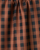 The Fall Gingham tea towel by GEOMETRY features brown fabric with a black checkered pattern and gentle gathers at the top, creating soft vertical folds—perfect as an ultra-absorbent addition to your kitchen.