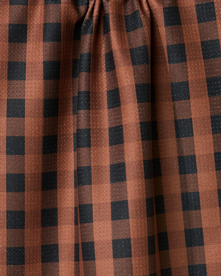 The Fall Gingham tea towel by GEOMETRY features brown fabric with a black checkered pattern and gentle gathers at the top, creating soft vertical folds—perfect as an ultra-absorbent addition to your kitchen.