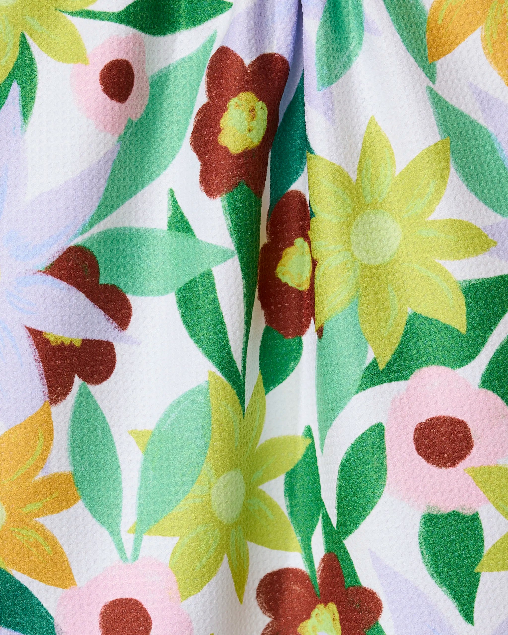 The GEOMETRY Floral Fields tea towel features yellow, brown, pink, and lavender flowers with green leaves on a textured white background. Ultra-absorbent and vibrant, it adds a cheerful touch to your kitchen.