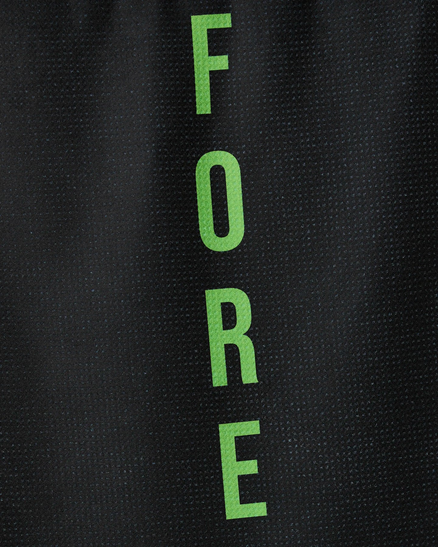 The GEOMETRY Fore tea towel features the word FORE in green capital letters arranged vertically on a textured black background. Made from recycled materials, it is quick-drying and eco-friendly.
