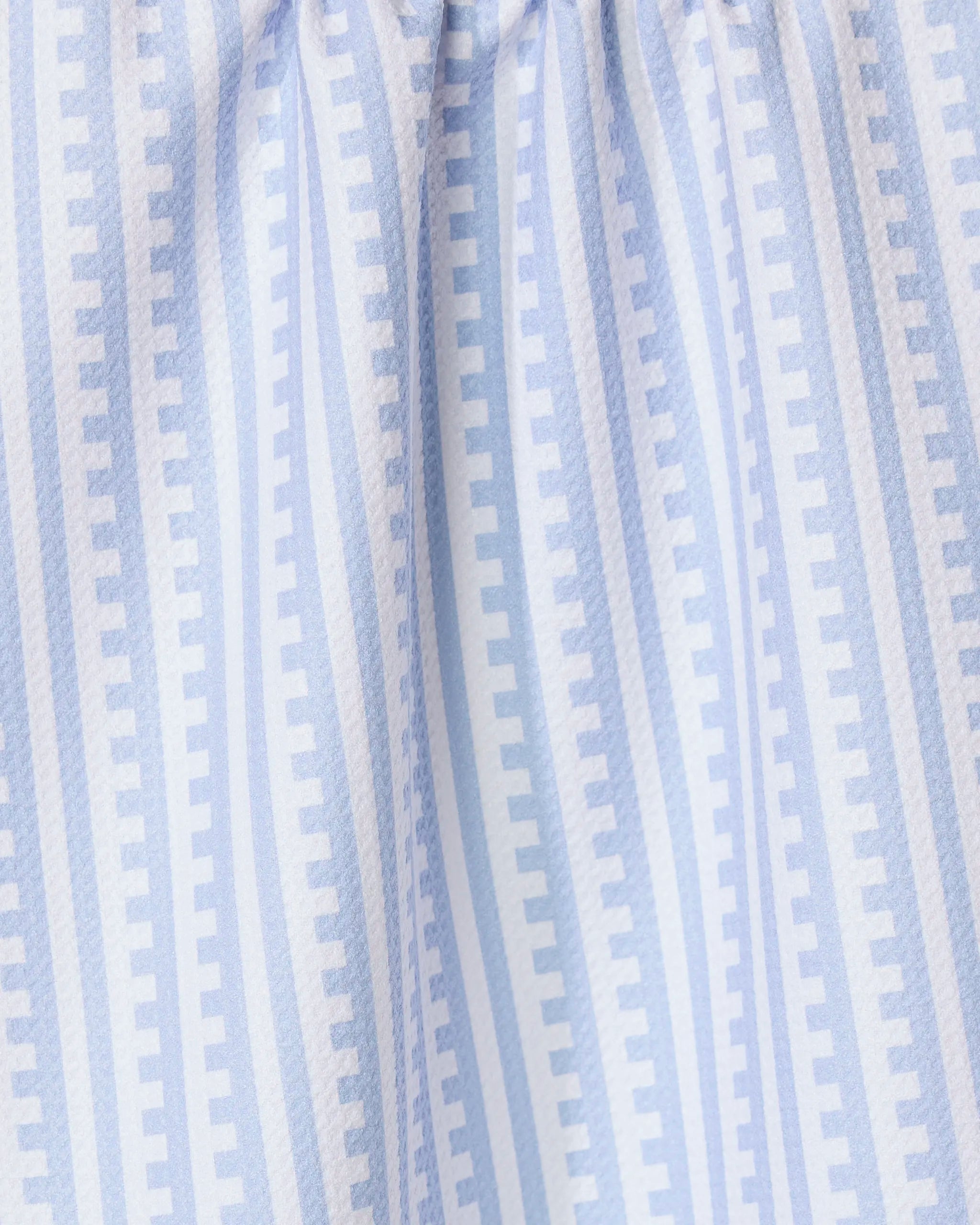 The GEOMETRY Fresh Linen tea towel features soft, gathered light blue and white stripes with a repeating pattern of small rectangles for a modern geometric look and textured feel, perfect for any kitchen.