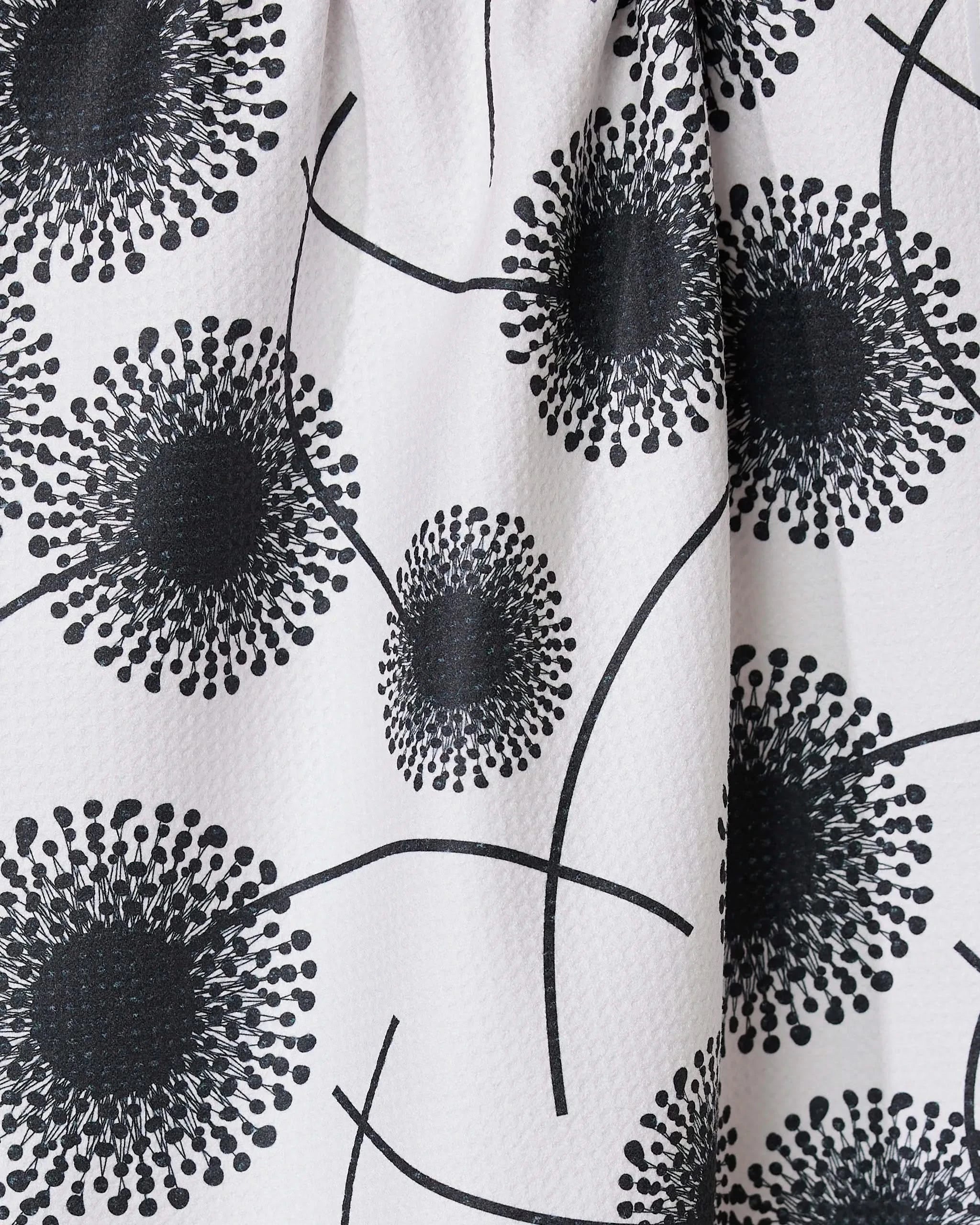 The Fully Bloomed recycled kitchen towel by GEOMETRY features a modern graphic pattern of large black abstract dandelion shapes linked by curved lines.