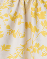 The GEOMETRY Garden of Gold tea towel showcases a close-up of its textured white fabric, adorned with a yellow botanical pattern of leaves and branches. Ultra-absorbent material is softly gathered at the top, creating gentle folds.