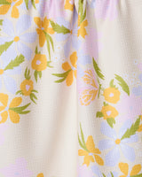 The GEOMETRY Abloom kitchen towel features a close-up of absorbent, slightly textured fabric with a pastel floral pattern—yellow, white, and purple flowers with green leaves on a light beige background.