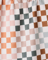 A close-up of the GEOMETRY Autumn Checkers towel shows its ultra-absorbent, crinkled fabric with a checkered pattern in muted pink, brown, gray, and white. Even lighting highlights the unique texture and evenly spaced squares.