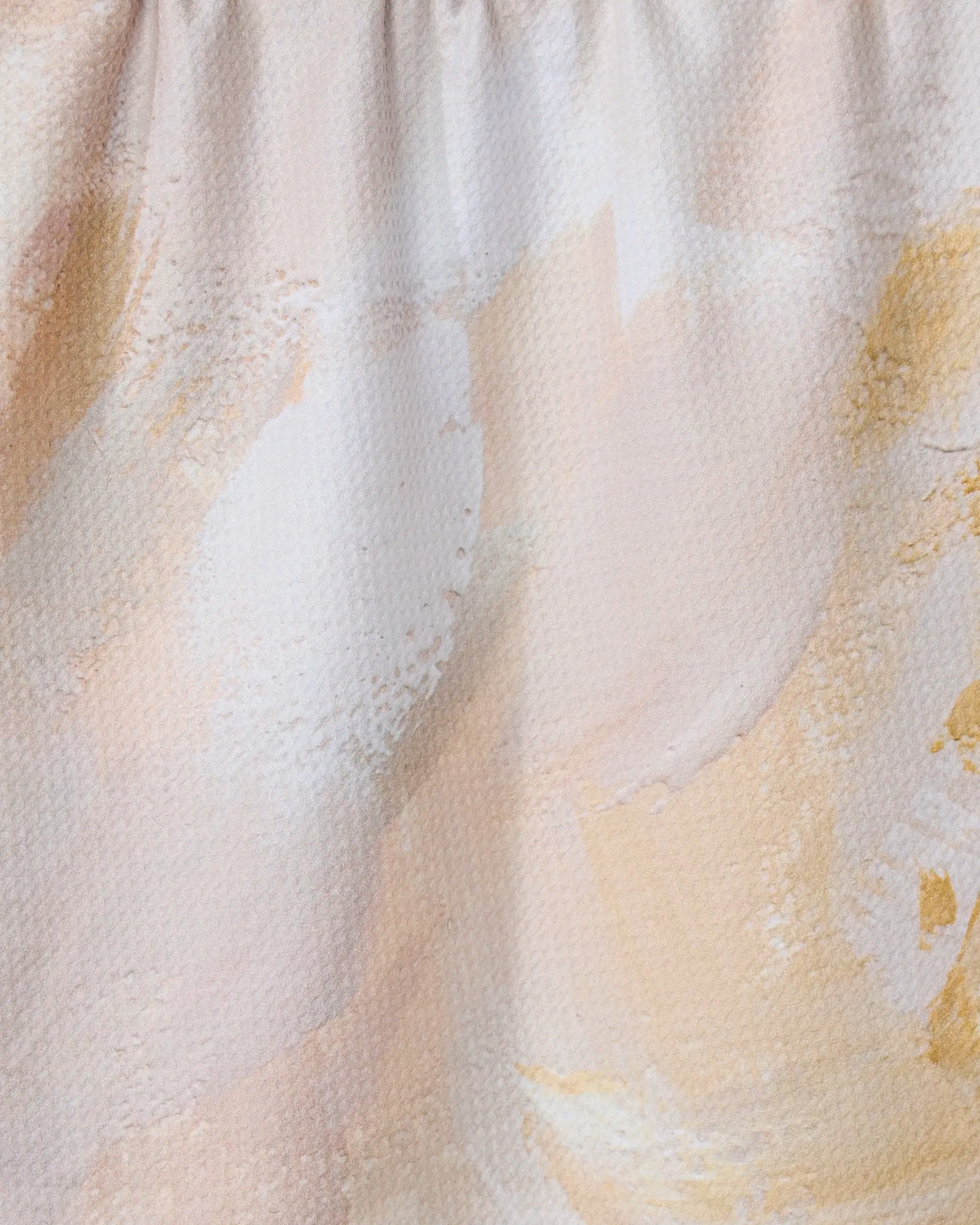The GEOMETRY Acete tea towel features a textured, abstract close-up with soft pastel brush strokes in beige, cream, and pale yellow, plus subtle folds and gathered sections at the top.