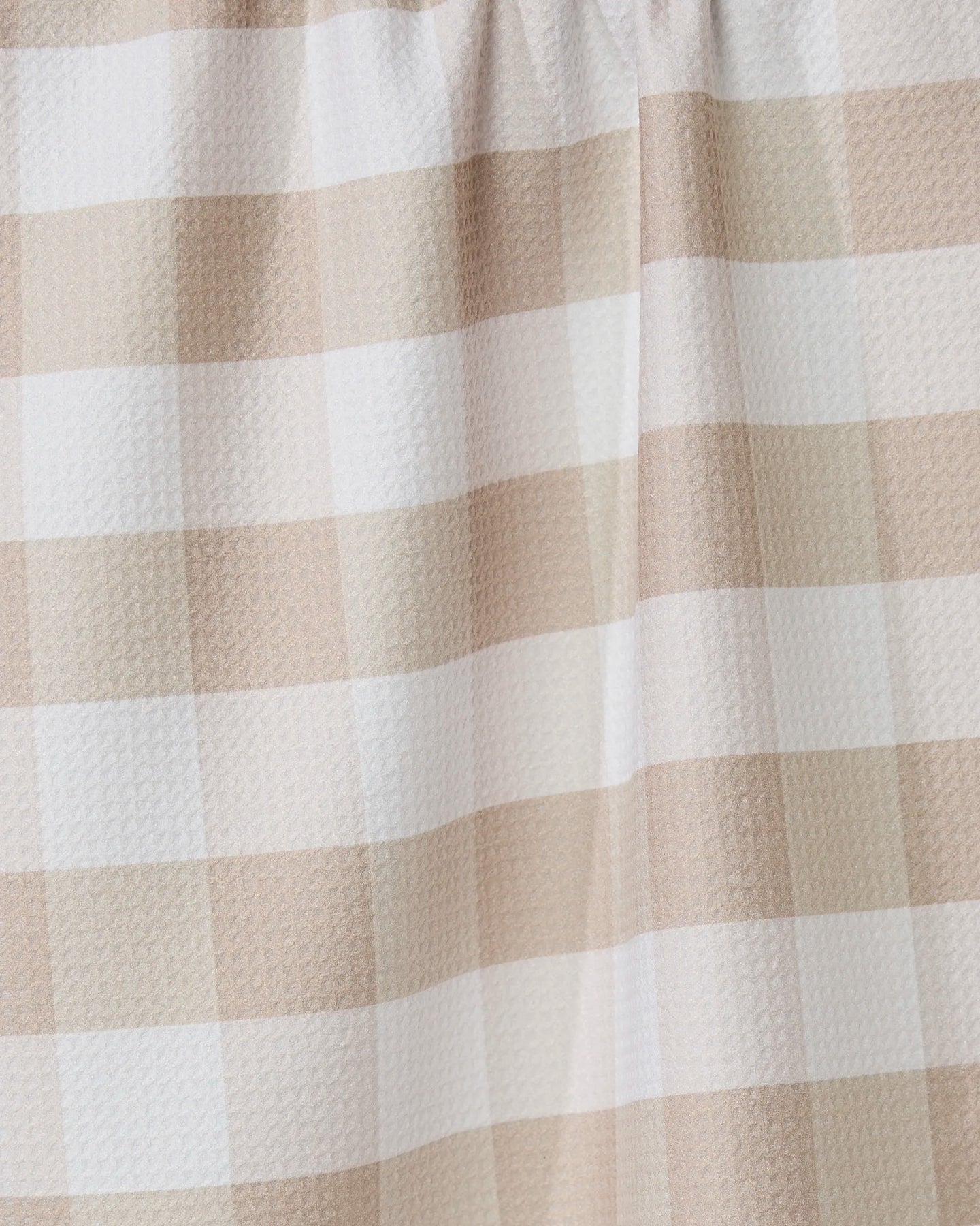 Close-up of the GEOMETRY Betty Bakes tea towel in beige and white gingham, highlighting its textured, eco-friendly fabric and gentle folds—an absorbent, stylish kitchen accessory.