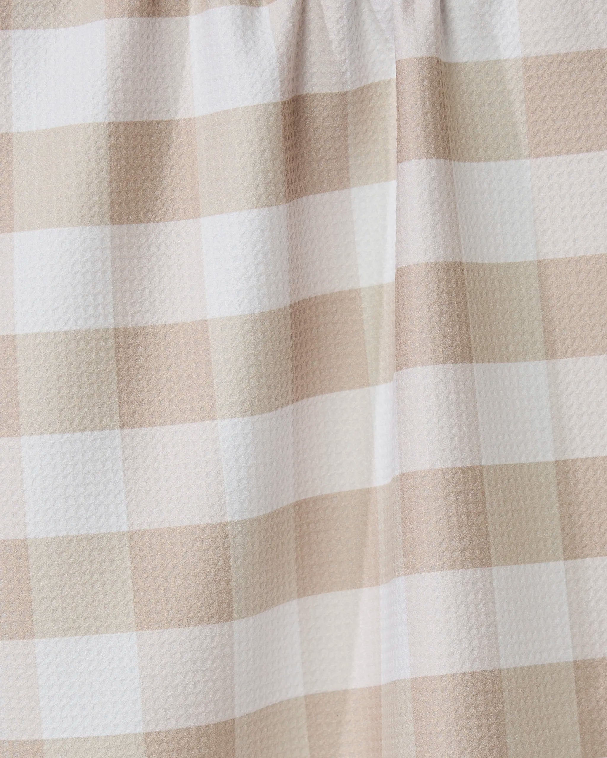 Close-up of the GEOMETRY Betty Bakes tea towel in beige and white gingham, highlighting its textured, eco-friendly fabric and gentle folds—an absorbent, stylish kitchen accessory.