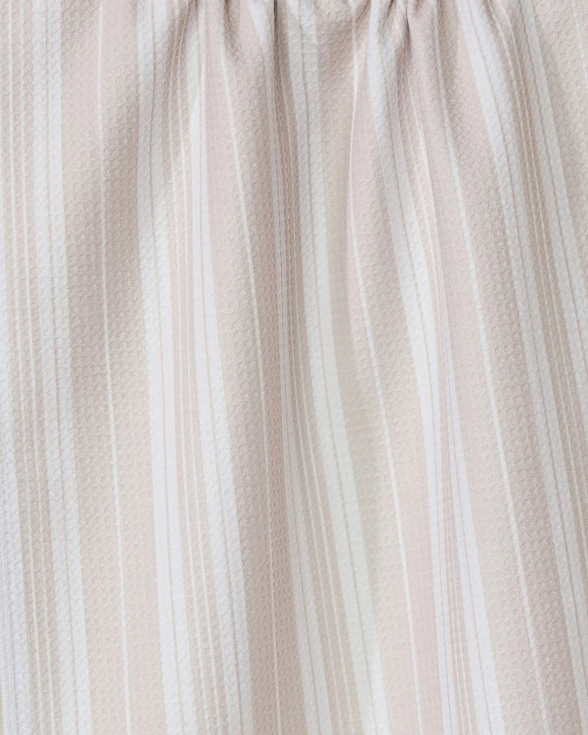 The GEOMETRY Betty Beach kitchen towel features light beige and white vertical stripes, gathered to create a soft, textured pattern with gentle folds and shadows.