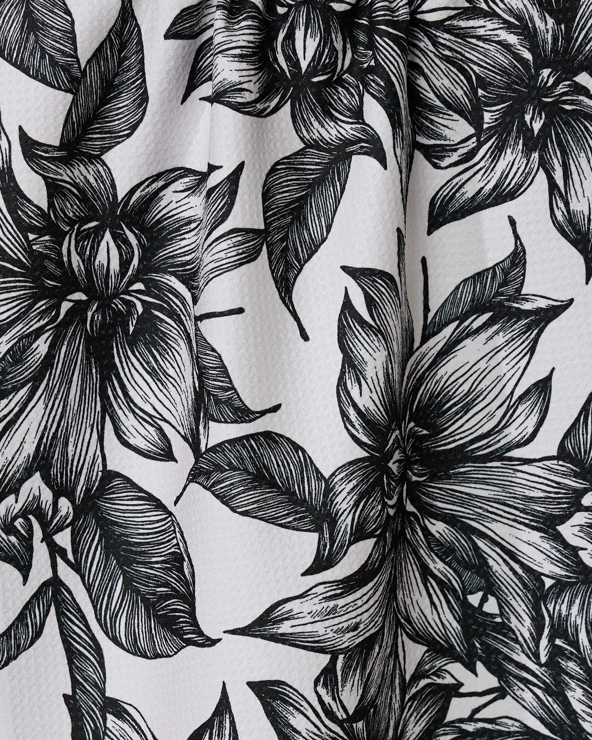 Black and white illustration of large, detailed flowers with leaves on a textured GEOMETRY Caring tea towel, crafted from ultra-absorbent recycled materials.