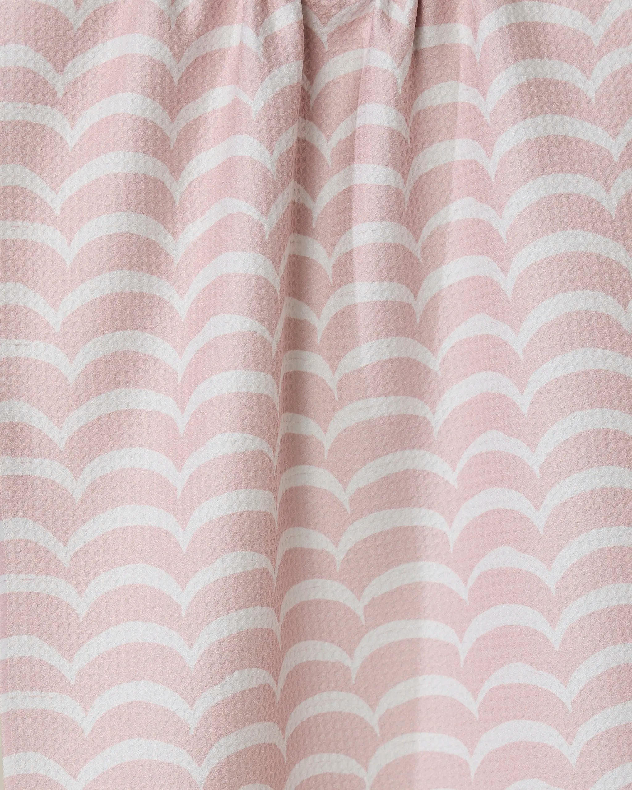 Close-up of the Cascading Pink eco-friendly kitchen towel by GEOMETRY, featuring a light pink color with a white wave pattern, soft folds, and a textured surface.