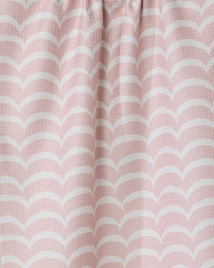 Close-up of the Cascading Pink eco-friendly kitchen towel by GEOMETRY, featuring a light pink color with a white wave pattern, soft folds, and a textured surface.