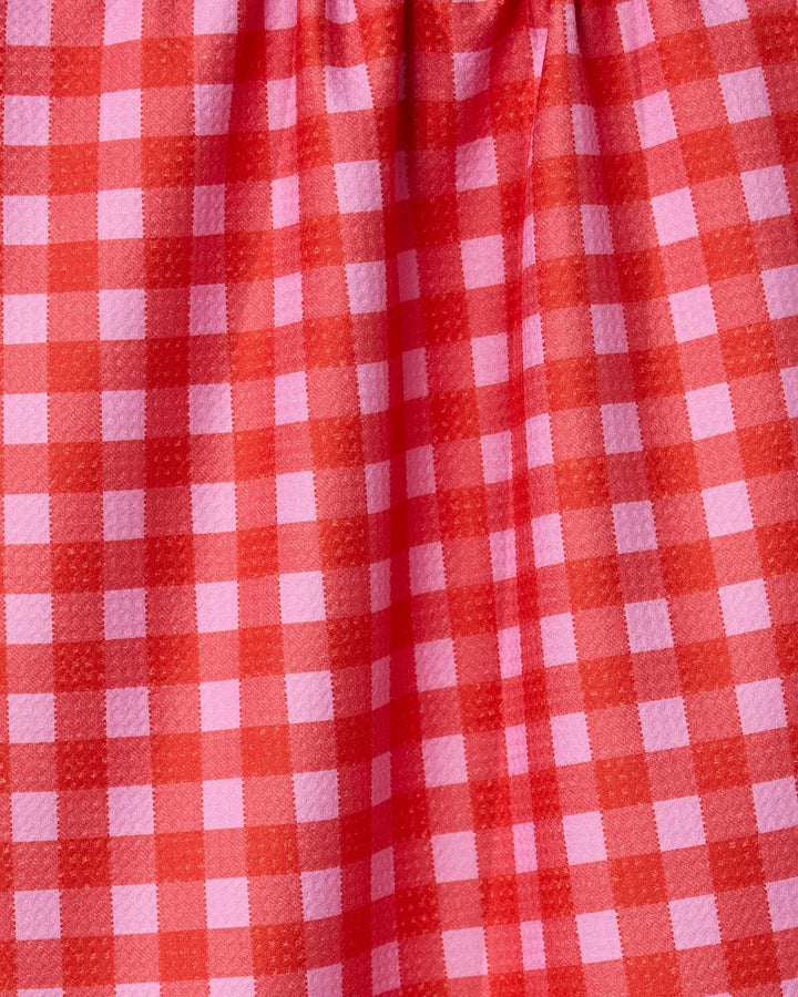 A close-up of GEOMETRYs Cherry Gingham fabric, showcasing its red and pink checkered pattern made from recycled materials with gentle gathers at the top.