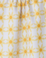 Close-up of the GEOMETRY Daisies kitchen tea towel, featuring a repeating yellow floral pattern with circular centers on white, ultra-absorbent textured fabric and gentle folds.