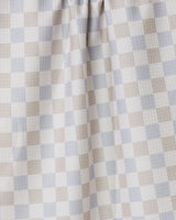 A close-up of the Danse Neutre quick-drying towel by GEOMETRY, featuring a checkered pattern in soft beige, light gray, and white. The fabric is gently gathered at the top, highlighting its texture and folds.