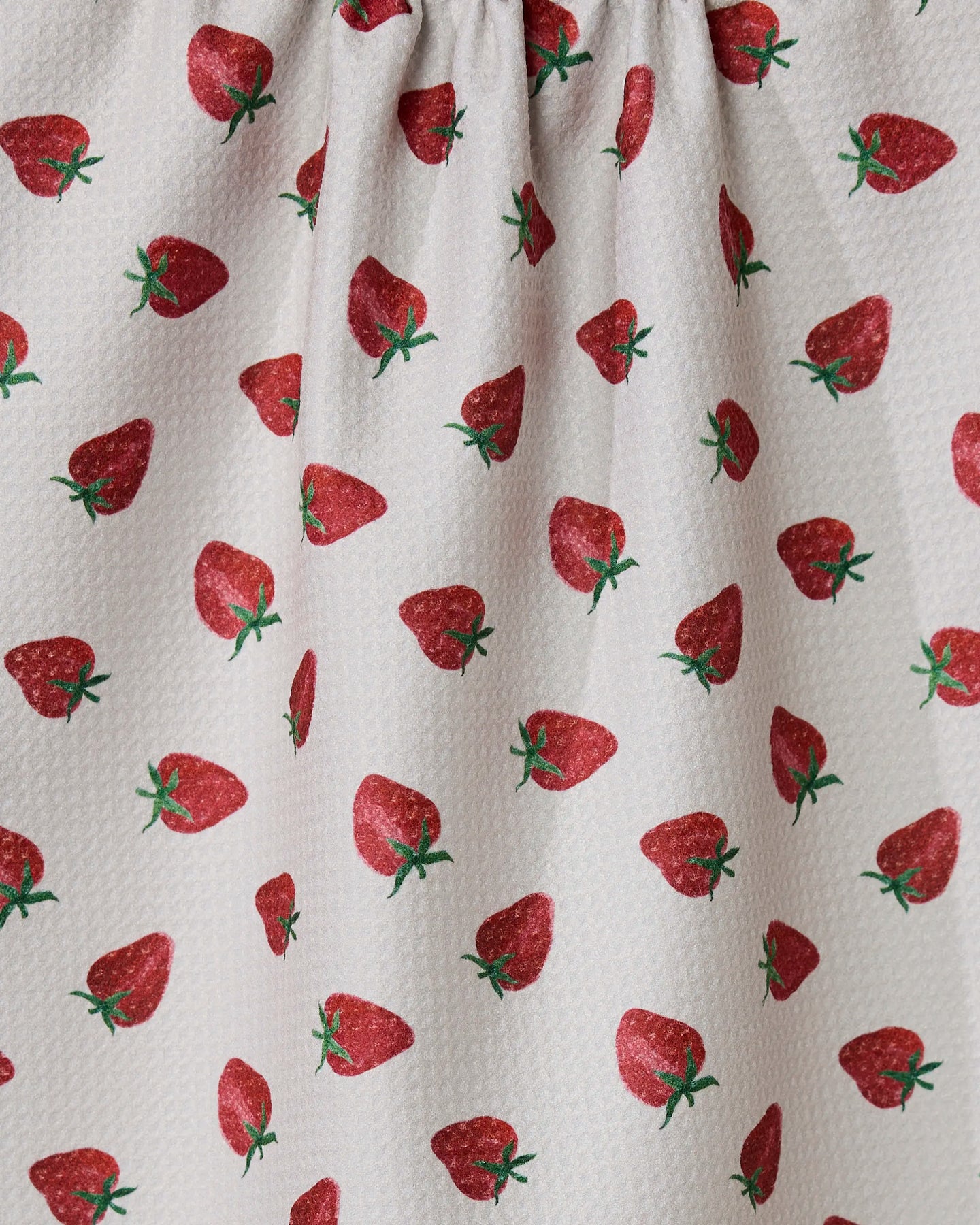 The Berry Patch tea towel by Geometry features a textured white fabric with a repeating red strawberry pattern and green stems. Ultra-absorbent and made from recycled materials, it’s perfect for your kitchen.