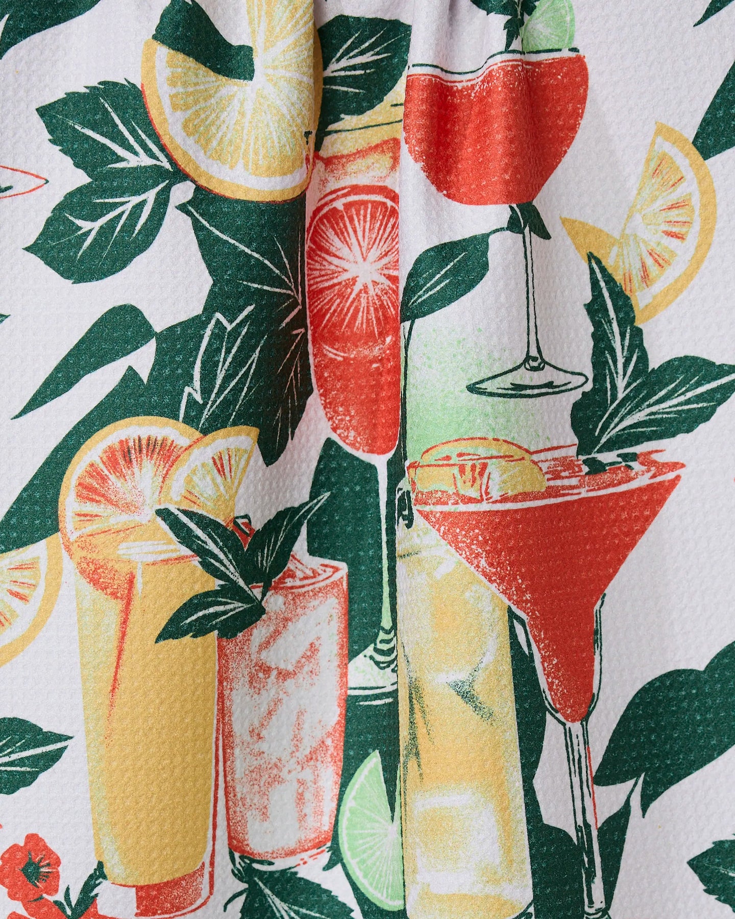 Summer Refreshments by Geometry is a tea towel with a vibrant pattern of illustrated cocktails, citrus fruits like lemon and lime, and green leaves on a textured white background.