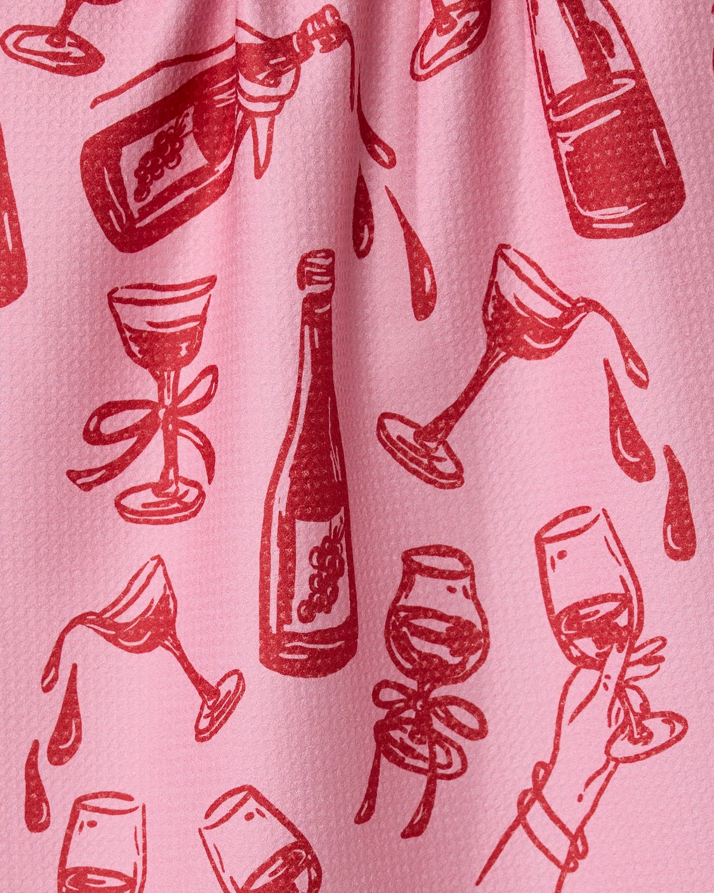 The Geometry Wining and Dining tea towel features a red wine-themed illustrated pattern on pink fabric—bottles, glasses, and more—for a stylish, quick-drying addition to your kitchen.