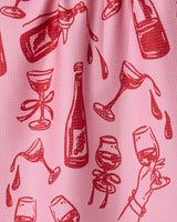 The Geometry Wining and Dining tea towel features a red wine-themed illustrated pattern on pink fabric—bottles, glasses, and more—for a stylish, quick-drying addition to your kitchen.