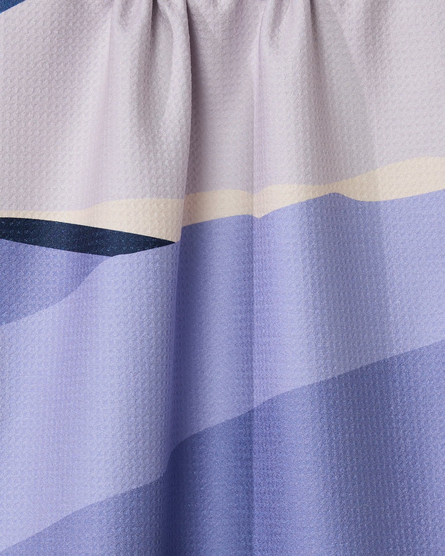 Close-up of GEOMETRYs Mountainous curtain, showcasing gathered recycled fabric with textured horizontal stripes in blue, lavender, and pale yellow.