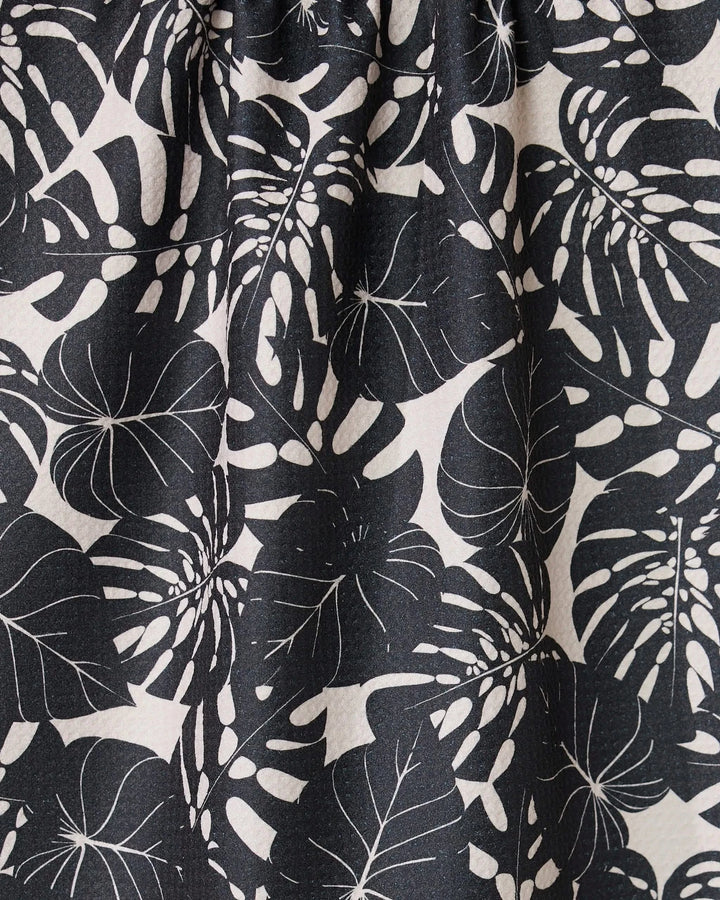 Close-up of GEOMETRYs Neutral Leaves tea towel, made from ultra-absorbent fabric with a black and white stylized monstera leaf pattern on a light background. Fabric is slightly gathered at the top.
