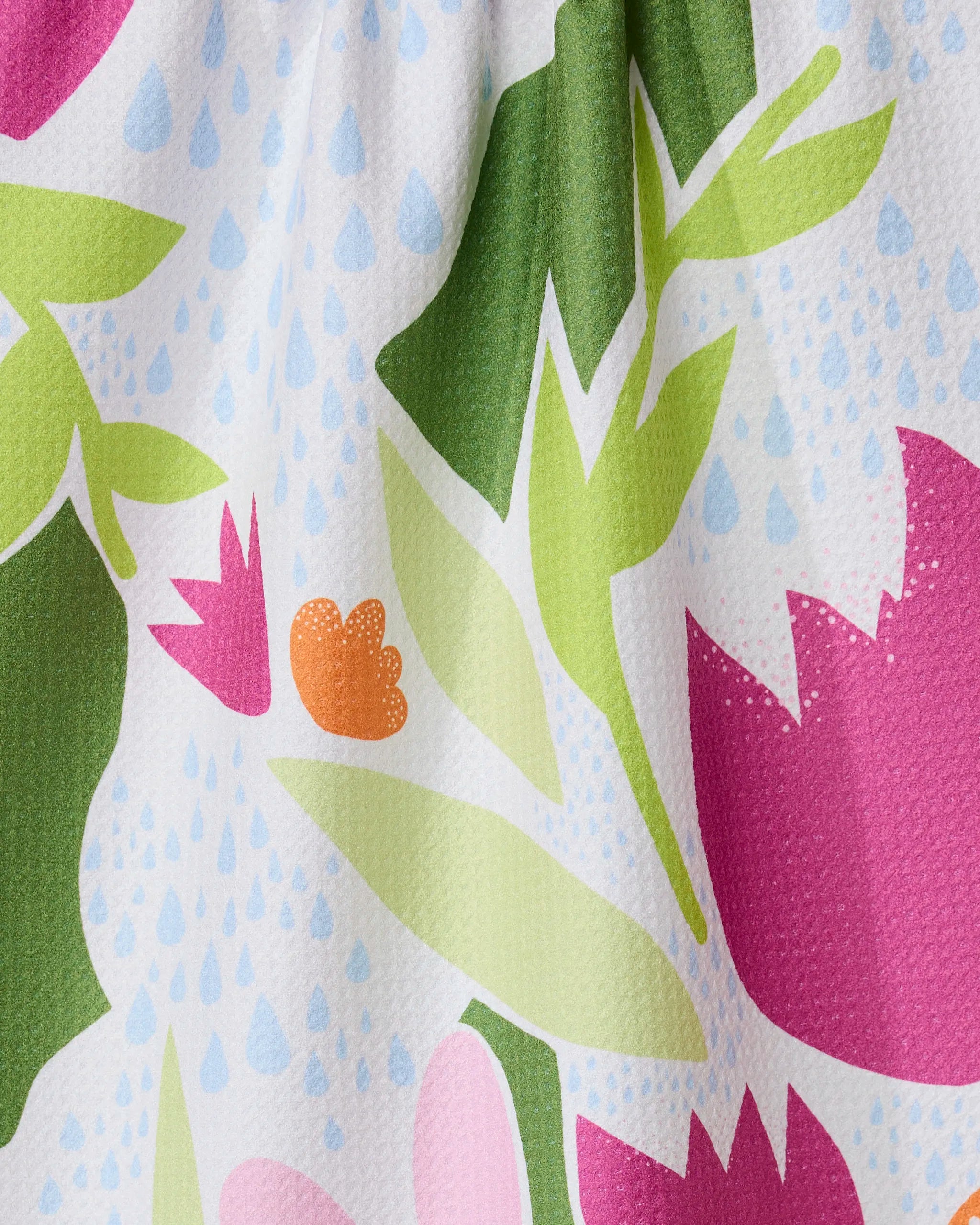 The GEOMETRY Paper Fields recycled kitchen towel features a colorful floral pattern with pink, green, and orange leaves plus blue raindrops on textured white fabric, adding cheerful charm to any space.