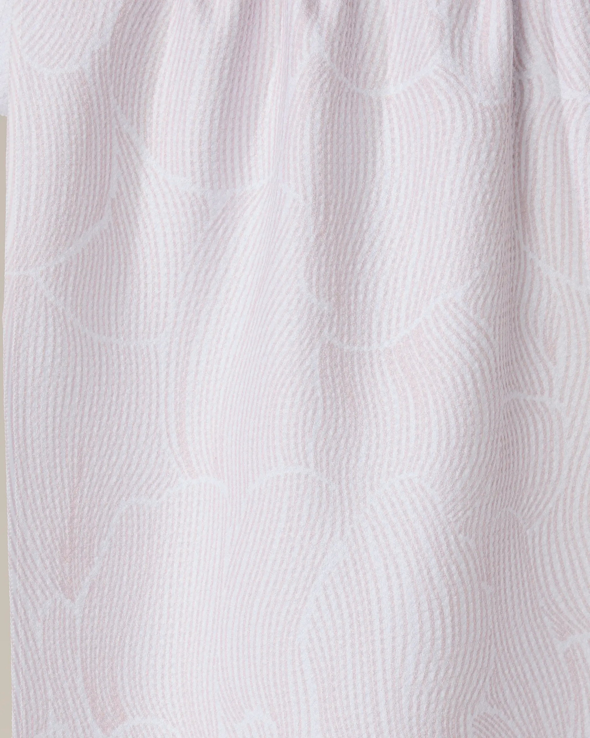Close-up of the Geometry Posh Petals Blushed Bergamot tea towel, featuring a light pink and white wavy textured pattern with gathered folds, crafted from recycled materials.