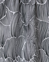 The Geometry Posh Petals Fresh Linen towel features a black and white abstract pattern with curved, vertical lines forming leaf-like shapes, adding movement and texture to this ultra-absorbent and stylish textile.