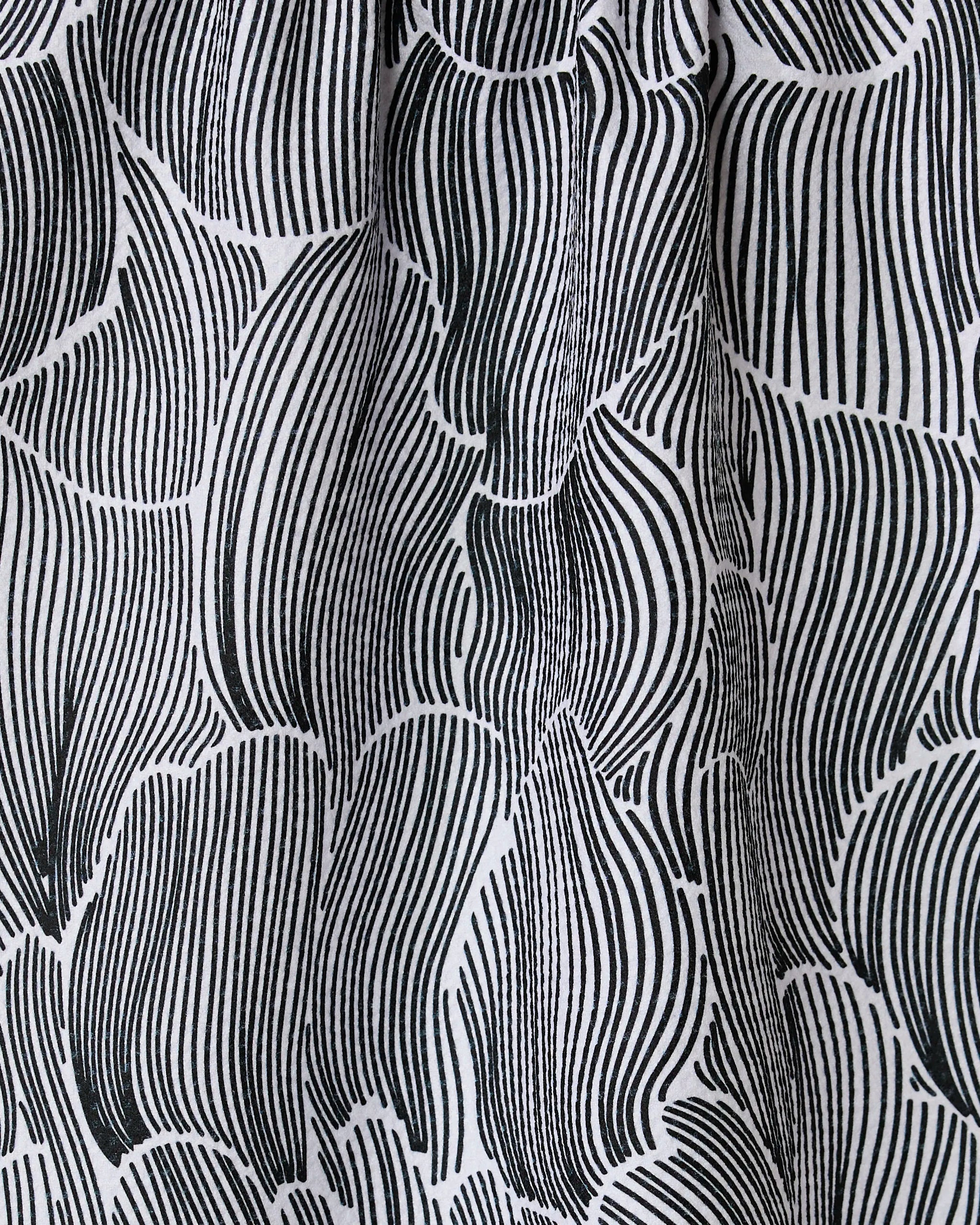The Geometry Posh Petals Fresh Linen towel features a black and white abstract pattern with curved, vertical lines forming leaf-like shapes, adding movement and texture to this ultra-absorbent and stylish textile.
