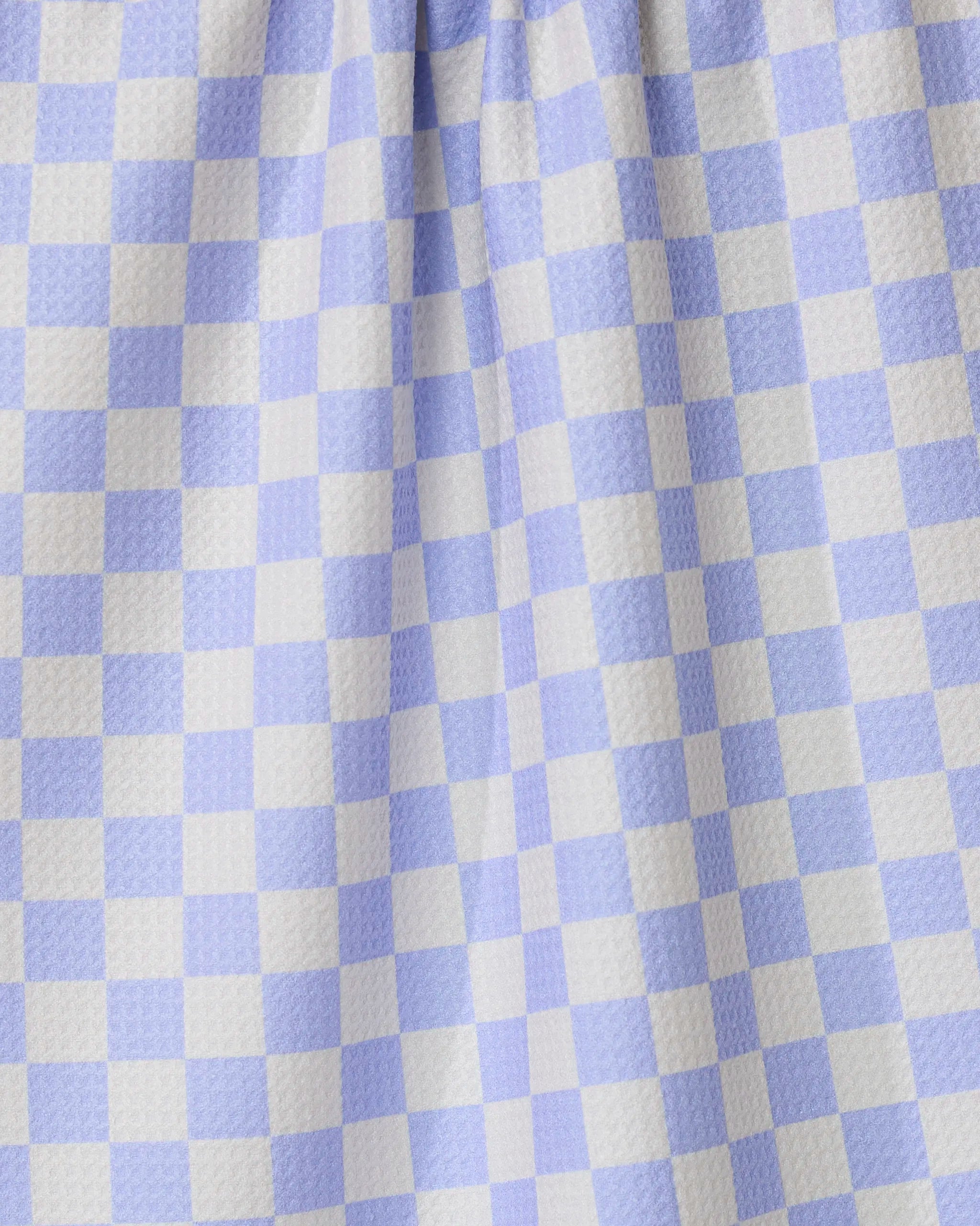 Close-up of Purple Picnic by GEOMETRY, featuring purple and white gingham checkered fabric with a textured surface and gentle folds—perfect for an ultra-absorbent tea towel in any kitchen.