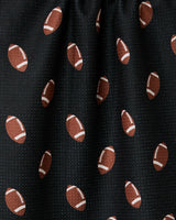 A close-up of GEOMETRYs Quarter Back ultra-absorbent black fabric, featuring a repeating pattern of brown footballs with white laces and stripes—slightly gathered at the top and perfect for a sporty tea towel.